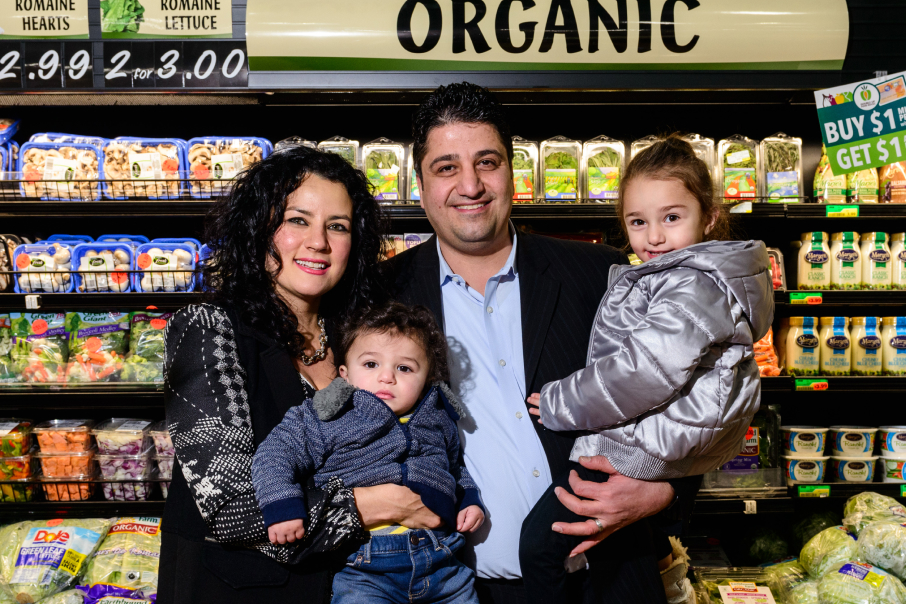 A family poses in front of an organic produce section at the supermarket.