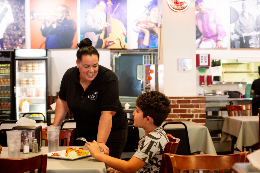 Restaurant owner of Lola's Cuban Food speaks with child customer