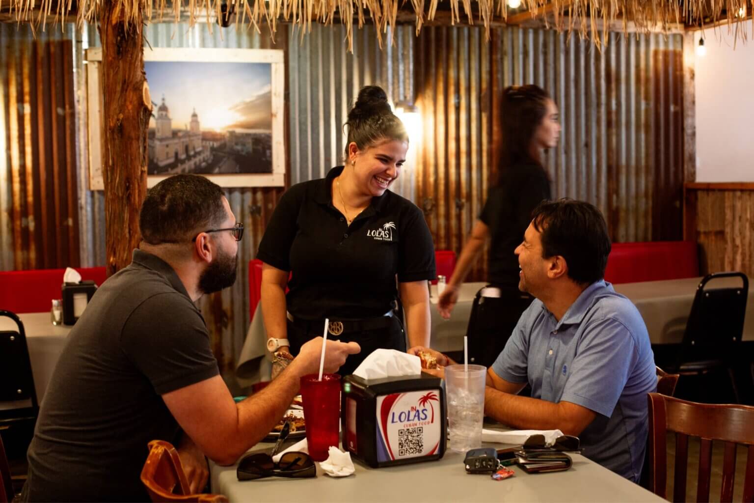 Lola's Cuban Restaurant customers at a table with Latino entrepreneur store owner