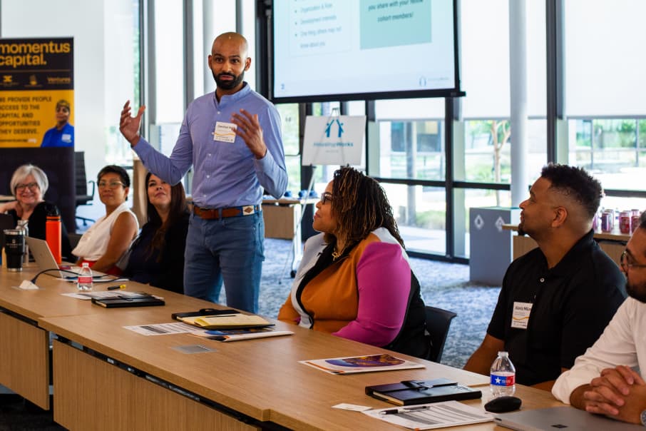 A man speaks in front of a diverse group during a real estate development training session.
