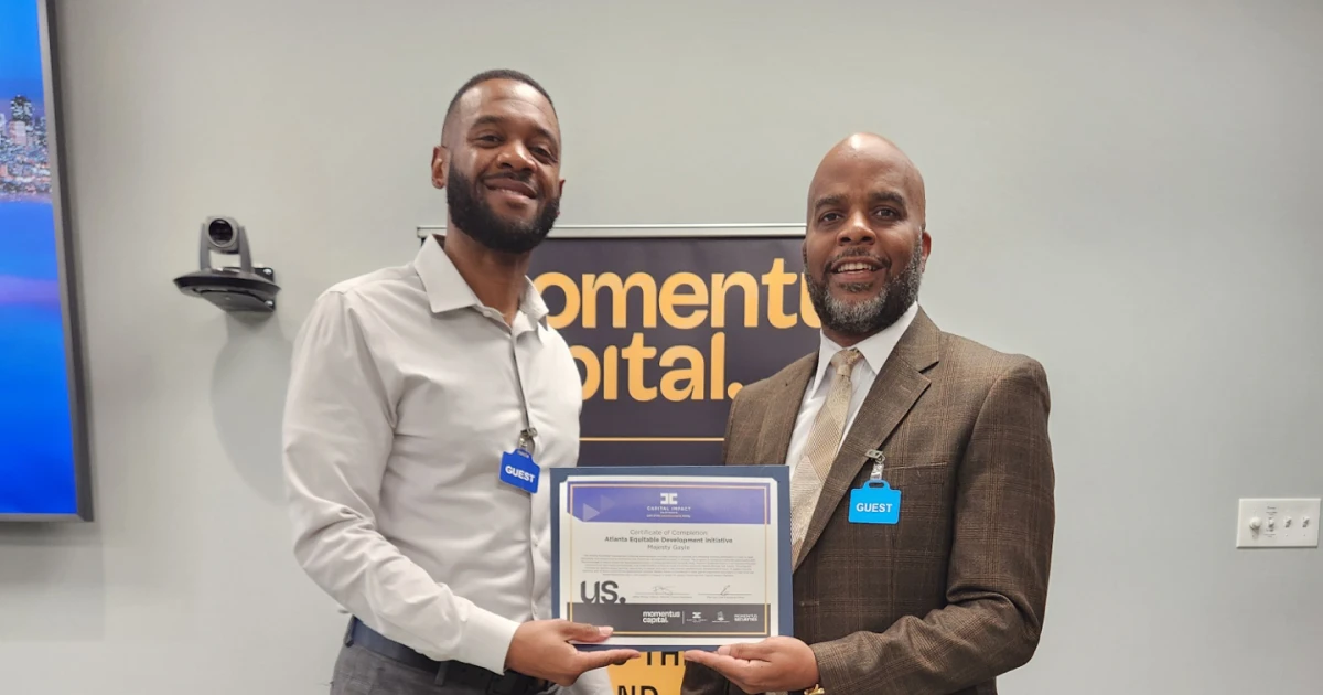 A real estate developer poses while receiving a certificate of graduation from Momentus Capital’s Atlanta EDI program.