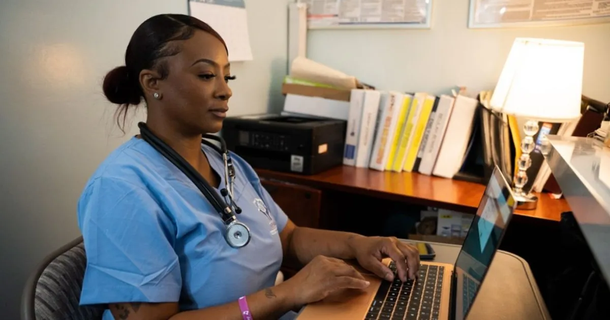 Nurse with scrubs and stethoscope works in an office setting for her wellness clinic.