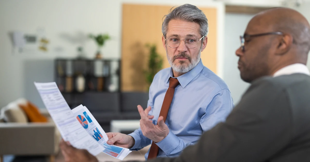 Two men analyze financial documents in an office.