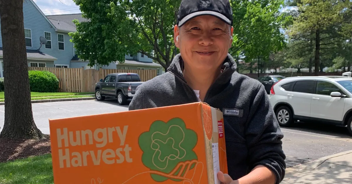Person holding a Hungry Harvest produce box for healthy food delivery programs supported by mezzanine financing from Momentus Capital.